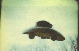 A single frame from Adamski's best-known 1965 color 8mm film of a scout ship over a wooded Maryland landscape, shot shortly before his death. Per Coker's analysis, the apparent bending of the saucer is warping of the thick Dynacolor film emulsion, visible also in the background trees.