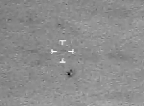 Enlarged detail of the object beneath the tracking cross-hairs. On this thermal palette black is hot: the object reads hotter than the surrounding air, with no wings, rotor, exhaust plume, or navigation lights resolving at the sensor's resolution.