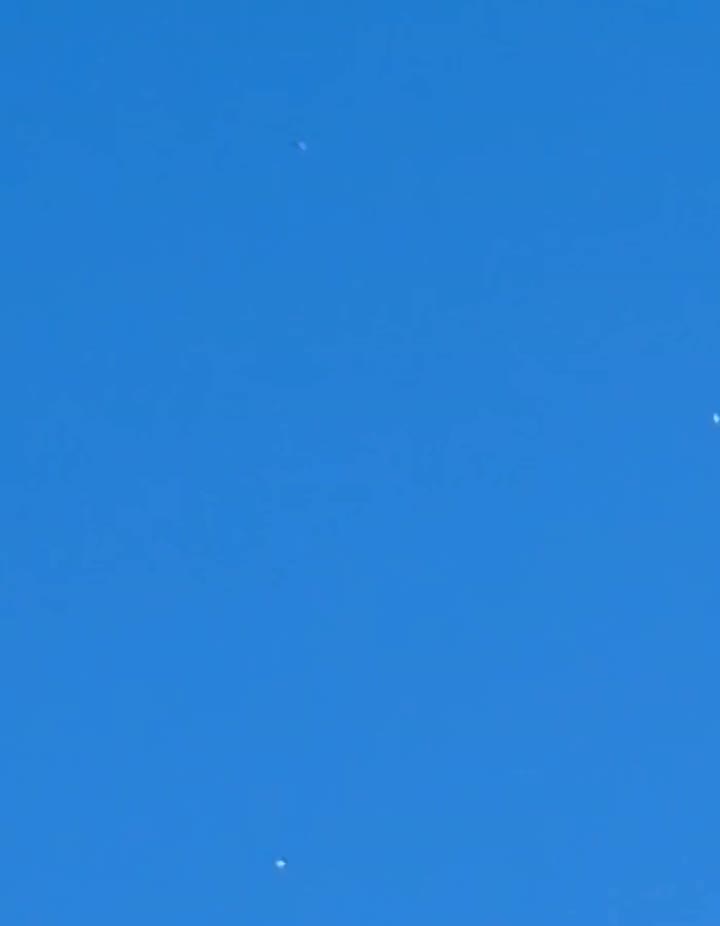 A zoomed crop showing several of the pale orbs against the daytime sky over Baltimore.