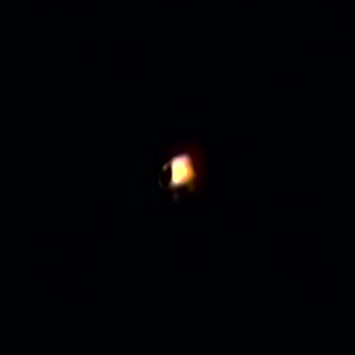 A zoomed crop of the orb from the same footage. It reads as a soft amber glow with no visible structure or navigation lights.