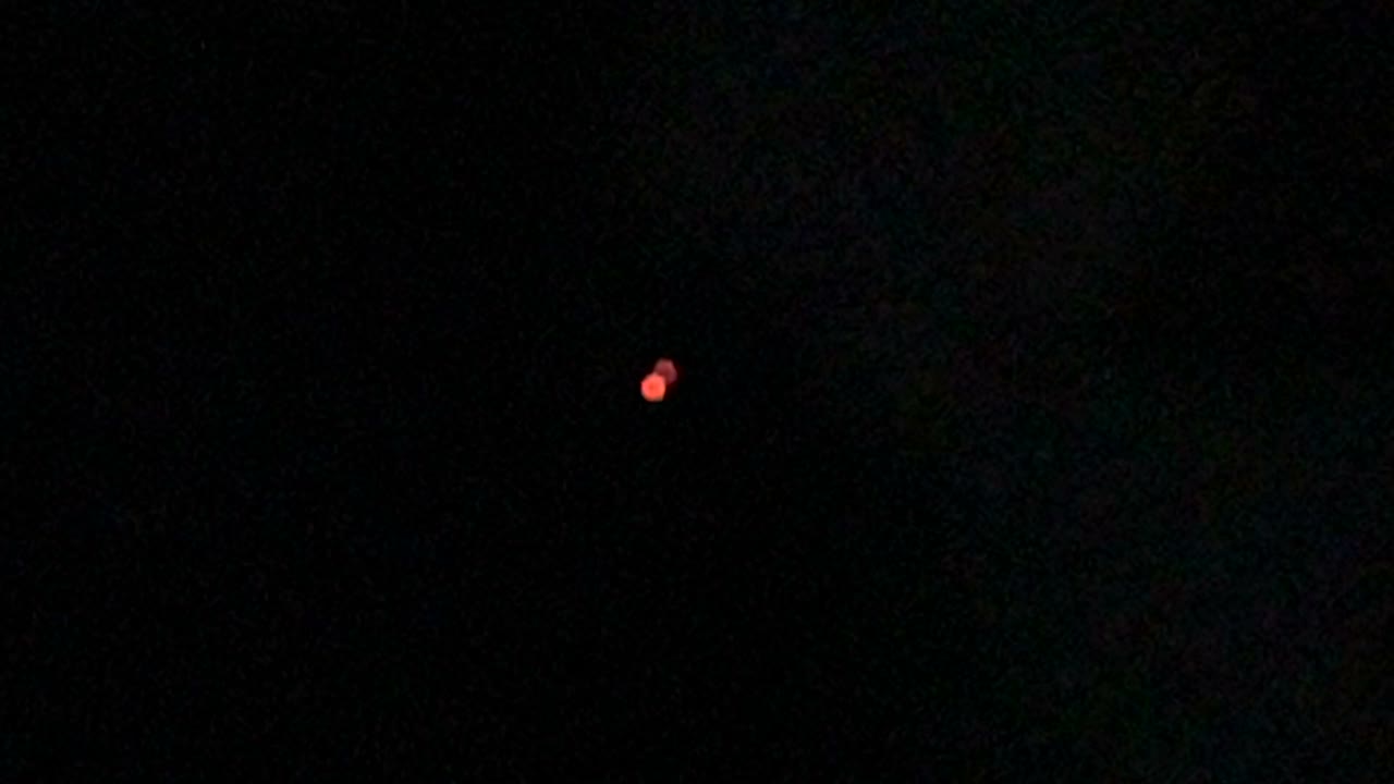A frame from FBI-UAP-PR002, the March 2022 iPhone 12 Pro clip: two red luminous sources near the horizon, the lower one slowly rotating relative to the upper. Public domain, U.S. Government (FBI) via DVIDS.