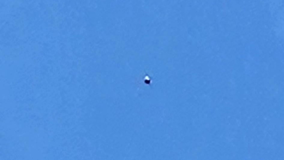 The second photograph, again isolating a single sphere with a bright top and dark underside against clear sky. Witness photograph.