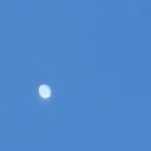 Enlarged detail of the object. At this distance it reads as a bright, rounded, slightly oval white shape with no wings, tail, or navigation lights resolving.