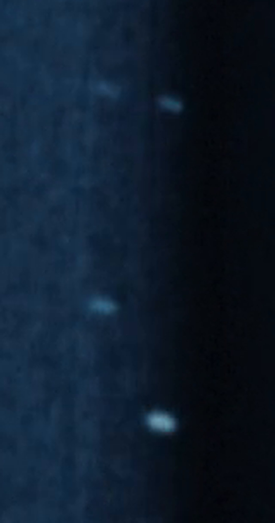 Three of the objects in the National Archives digitization of the Tremonton film, released by the Department of War on 18 September 2026 as DOW-UAP-PR159. This is a crop from the frame at 20 seconds, enlarged four times. The objects are soft-edged bright forms against open sky with no horizon and no landmark anywhere in frame, which is precisely the limitation the Project Blue Book file cites for being unable to determine their distance, size, altitude or speed.
