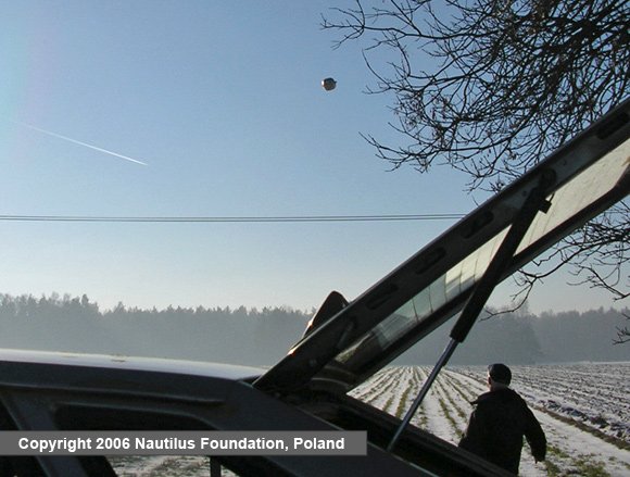 The object higher in the sky with one witness beside the car and a jet contrail visible, matching the account that it climbed swiftly before vanishing.